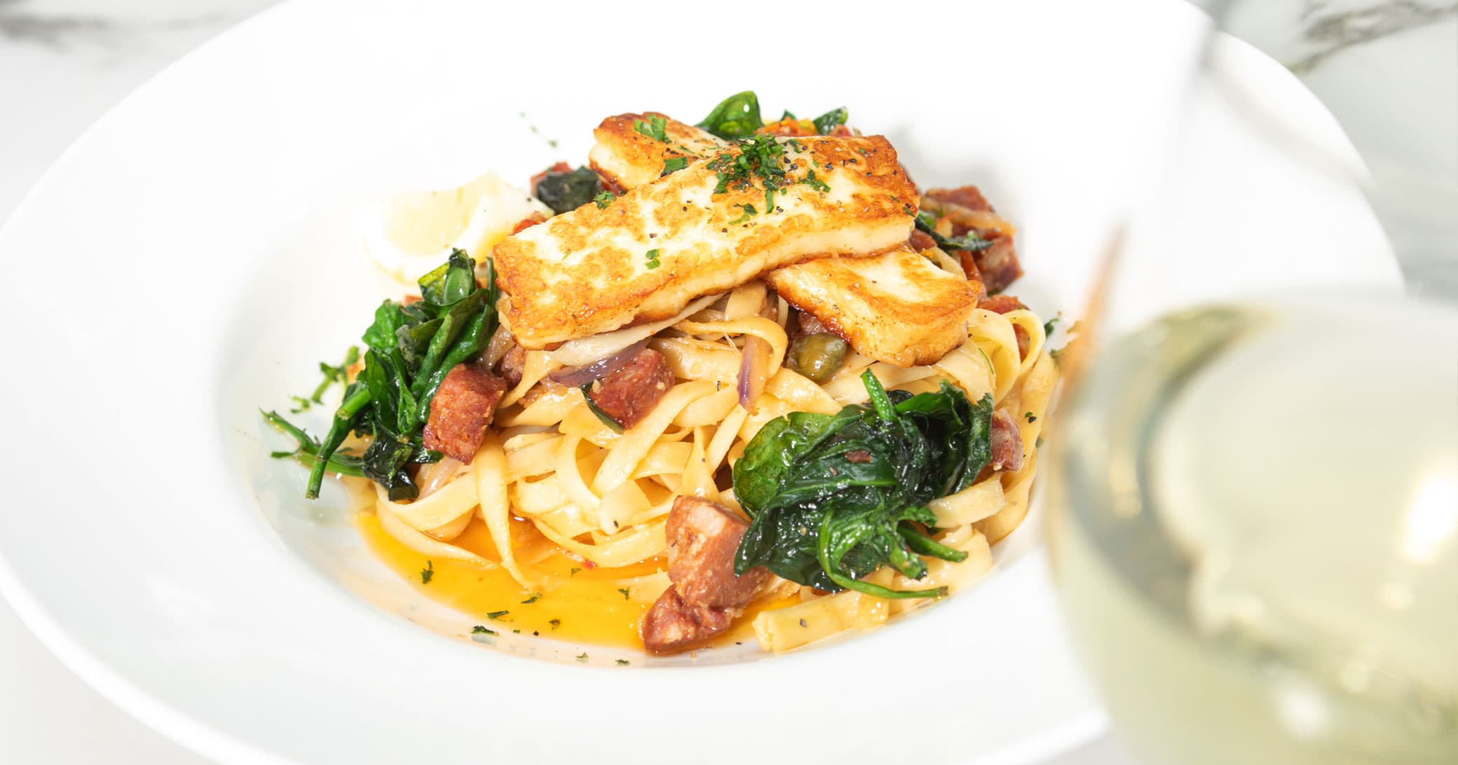 Fettuccine carbonara topped with grilled halloumi and wilted spinach at Queen St Cafe